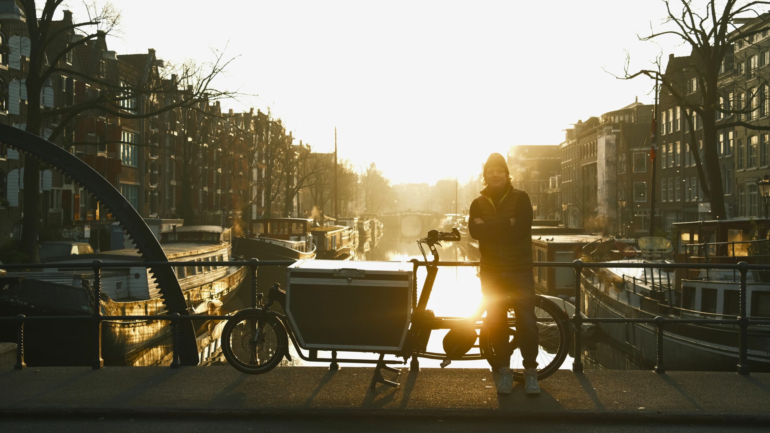 Handyman in Amsterdam met bakfiets op brug langs de gracht